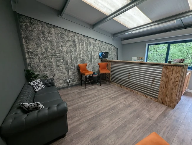 The HEtyres HEhub — sofa, coffee and a screen showing the workshop